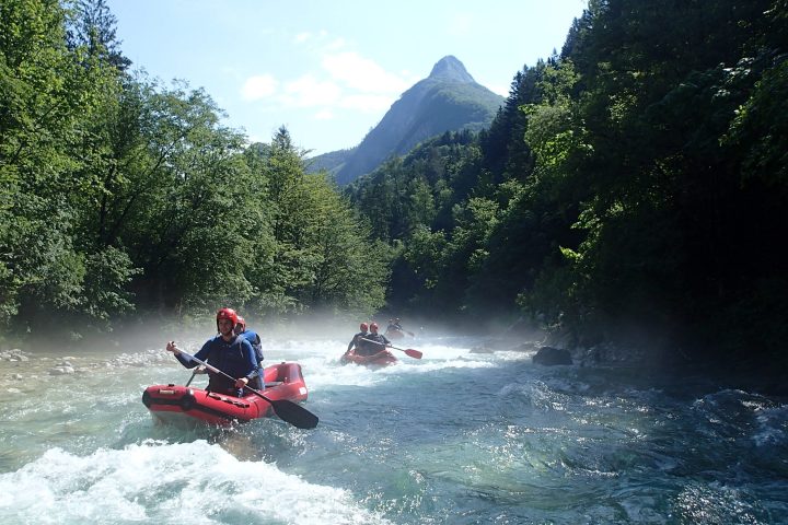 a man riding on the back of a boat next to a lake