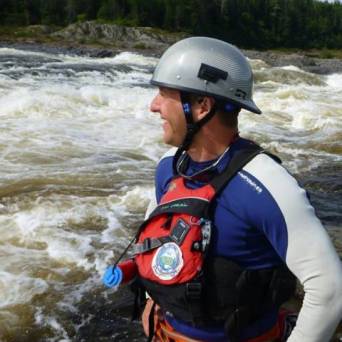 a man with a helmet on a raft in a body of water