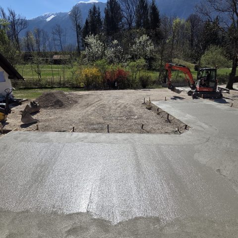 Fresh concrete being poured on a construction site with mountains in the background.